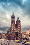 Fototapeta  - Church of St. Mary in the main Market Square in cloudy weather. Basilica Mariacka. Dramatic sky. Krakow. Poland.