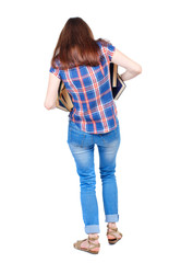 Girl comes with  stack of books. back side view. Rear view people collection.  backside view of person.  Isolated over white background. Girl in a plaid shirt is trying to keep falling out of the book