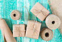 Gifts Packaged In Kraft Paper And  Jute Rope Constricted And Hank Jute Yarn With Sackcloth On Turquoise Painted Wooden Table