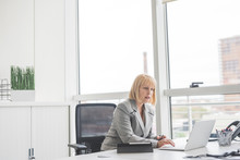Mature Businesswoman Reading Update On Office Laptop