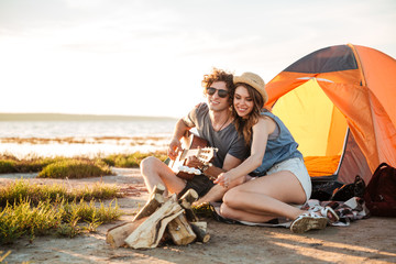 Poster - Couple playing guitar and frying marshmallows on bonfire together