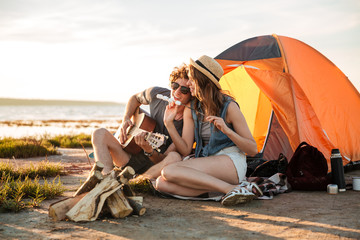 Poster - Couple playing guitar and eating fryed marshmallows near touristic tent