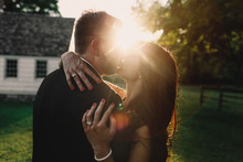 Rays Of Sun Hide The Tender Kiss Of Newlyweds Standing Outside