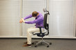 man stretching arms,exercising on chair in office, healthy lifestyle