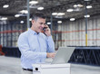 © Erik Isakson/Blend Images - Caucasian businessman using laptop and cell phone in empty warehouse