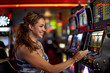 © Eric Raptosh Photography/Blend Images - Caucasian woman playing slot machine in casino