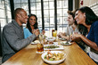 © Peathegee Inc/Blend Images - Smiling friends enjoying food and cocktails at table in bar