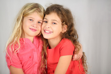 Two happy girls with long hair sitting hugging