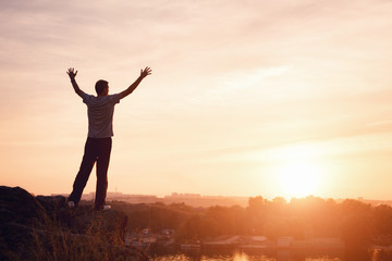 Wall Mural - silhouette of a man with raised-up arms at the beautiful sunset on the mountain. background
