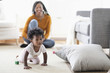 © JGI/Tom Grill/Blend Images - Black woman watching baby daughter crawl toward pillow