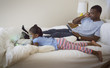 © Hello Lovely/Blend Images - African American father and daughter relaxing on bed