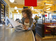 © Mark Edward Atkinson/Tracey Lee/Blend Images - African American woman reading newspaper in cafe
