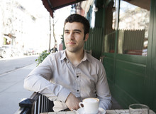 Hispanic Man Sitting At Sidewalk Cafe