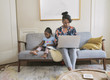 © Hello Lovely/Blend Images - African American mother and daughter relaxing in living room