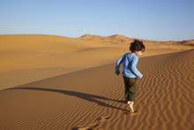 Mixed Race Boy Running In Desert