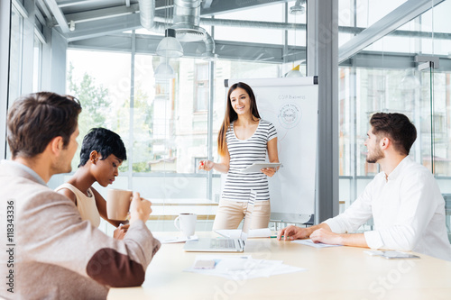 Fotografie, Obraz Smiling woman making presentation for business people in office