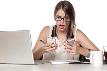 a young business woman looking at both two ringing phones