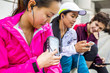 © Adam Hester/Blend Images - Runners using cell phones and earbud on city sidewalk