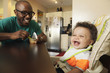 © Roberto Westbrook/Blend Images - Father feeding baby at table