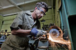 © Doug Berry/Blend Images - Caucasian man grinding metal in workshop