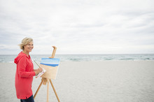 Older Caucasian Woman Painting On Beach