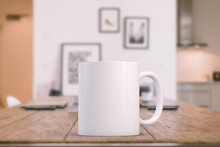 White Blank Coffee Mug On A Kitchen Table With Laptops In The Background, Ready For Your Custom Design/quote.