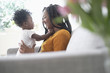 © JGI/Tom Grill/Blend Images - Black woman playing with baby daughter on sofa