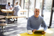 © Resolution Productions/Blend Images - Older man using digital tablet in cafe