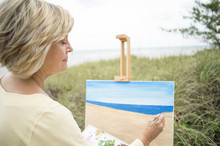 Older Caucasian Woman Painting Beach Outdoors