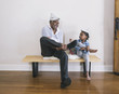 © Hello Lovely/Blend Images - African American grandfather and granddaughter playing on bench