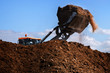 Excavator shovel working on a large heap of manure, organic fertilizer