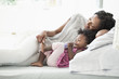 © JGI/Tom Grill/Blend Images - Black woman playing with foot of baby daughter on bed