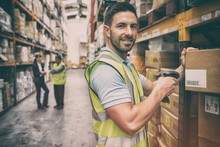 Warehouse Worker Scanning Box While Smiling At Camera
