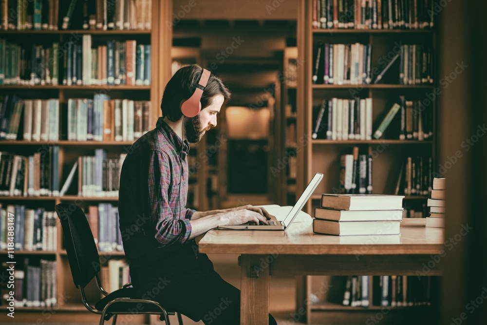 Hipster student studying in library - obrazy, fototapety, plakaty 