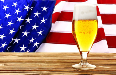 Wall Mural - Glass of beer on wooden table. USA flag background.