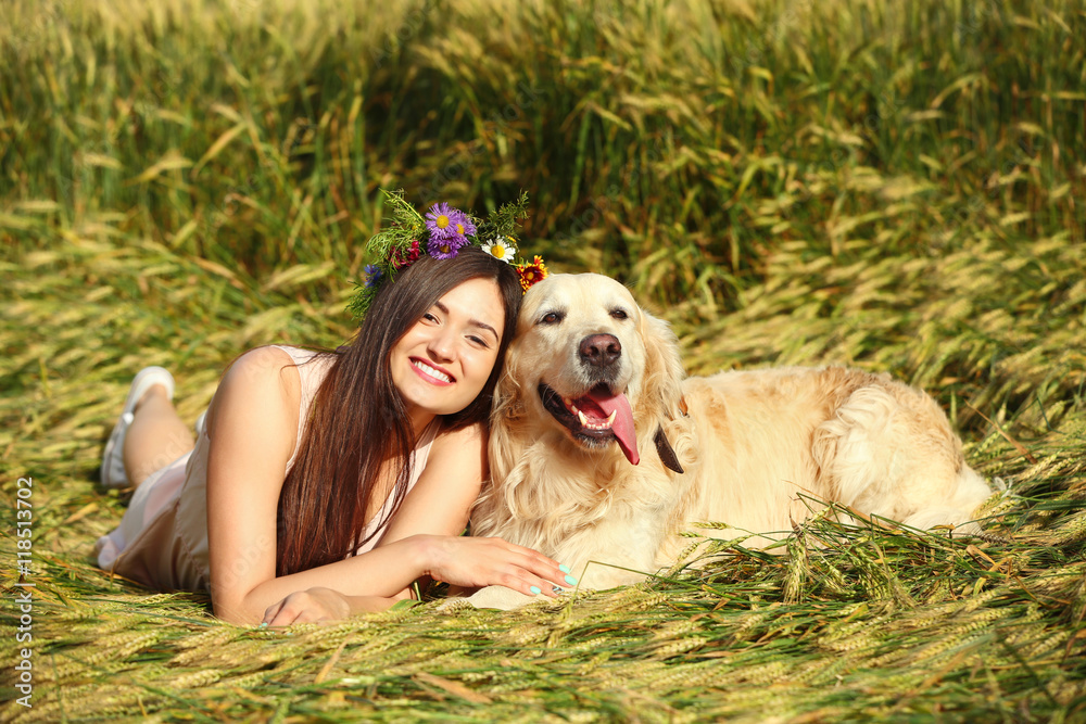 Beautiful girl with cute retriever in field
