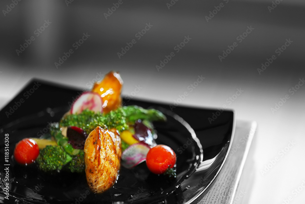 Fried chicken fillet with vegetables on black plate