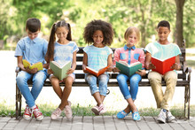 Cute Kids Reading Books On Bench