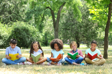 Poster - Cute kids reading books on green grass