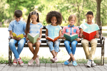 cute kids reading books on bench