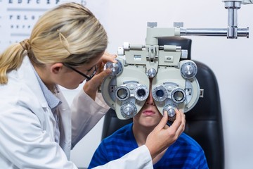 Wall Mural - Female optometrist examining young patient 