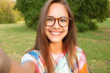 close up portrait of a young attractive woman holding a smartphone and taking a selfie