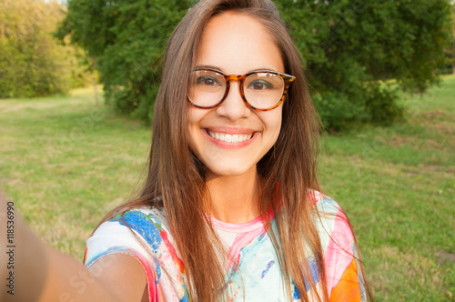 Cuadros en Lienzo Close up portrait of a young attractive woman holding a smartphone and taking a