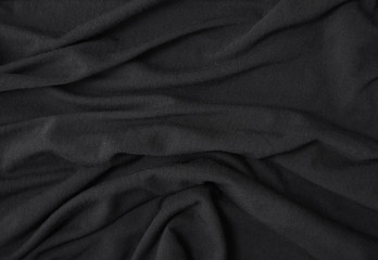 A full page close up of folds of soft black cotton fabric texture