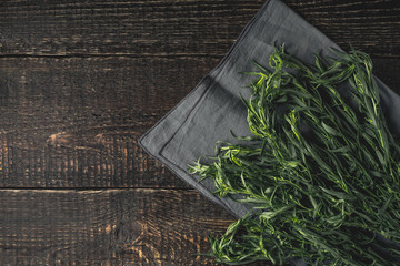 Wall Mural - Tarragon on the grey napkin on the wooden table top view