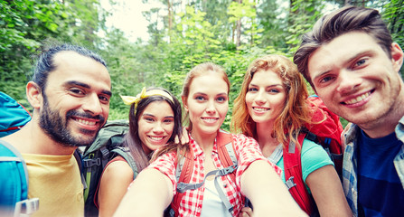 Canvas Print - friends with backpack taking selfie in wood