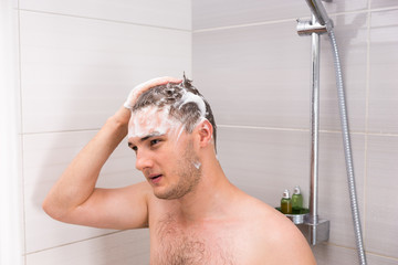 Wall Mural - Handsome man washing his foam hair in shower cabin