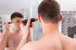 © kolotype - Man shaving his ear with trimmer in the bathroom