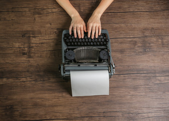 Wall Mural - Woman hands working with retro typewriter on wooden background