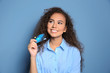 © Africa Studio - Attractive woman holding credit card on blue background